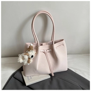Detail of pink woven tote bag featuring a leather strap and cute plush bear charm decoration