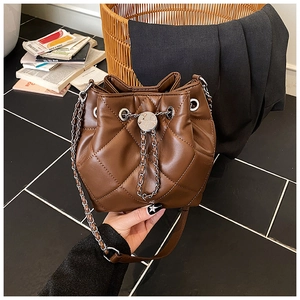 Close-up of quilted dark brown bucket bag with metal drawstring and chain strap detail