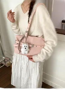 Pink faux leather tote bag detail with metal buckles and a cute white puppy plush charm