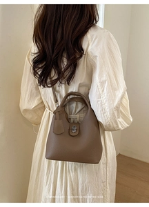 Detail view of a vintage dark brown lychee textured bucket bag with a metal twist lock