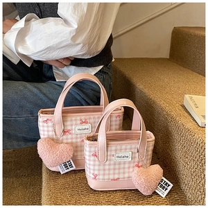 Detail of pink plaid bucket bags with bow patterns and plush heart charm on stairs