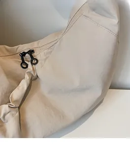 Detail shot of the beige dumpling bag featuring high-quality canvas fabric and dual zippers