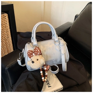 Detailed view of silver Boston bag with plush bear charm and beaded strap detail