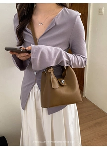 Detail of a brown lychee pattern leather bucket bag with metallic twist lock and charm
