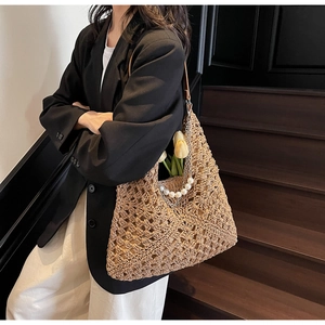Dettaglio della borsa tote in paglia con motivo a uncinetto e tracolla di perle eleganti