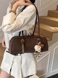 Deep brown matte leather baguette shoulder bag with cute plush bear charm on white stairs