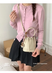 Detail of beige drawstring bucket bag with horse charm and adjustable long strap