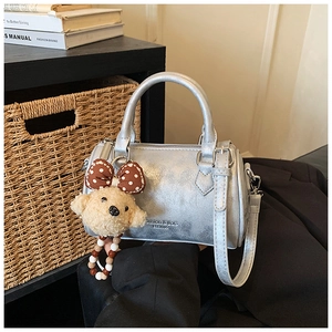 Detailed close-up of a silver cylinder bag with a plush puppy charm and a polka dot bow