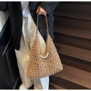 Dettaglio della borsa tote in paglia intrecciata con perle eleganti e catena
