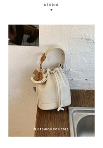 Close-up of off-white bucket bag with lychee texture leather and a wooden horse charm