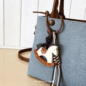 Dettaglio della borsa in pelle azzurra martellata con ciondolo a forma di cavallo