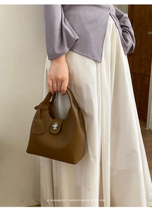 Detail of a brown lychee pattern leather tote bag featuring a silver metal twist lock
