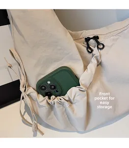 Close-up of beige dumpling bag featuring front storage pocket and double metal zippers
