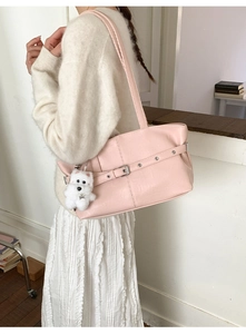 Detail of light pink faux leather tote bag with decorative buckle and plush dog charm