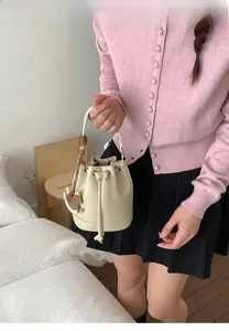 Detail of off-white leather bucket bag with drawstring closure and horse charm
