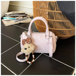 Close-up of pink Boston handbag with plush bear charm and Fashion & BaG logo details