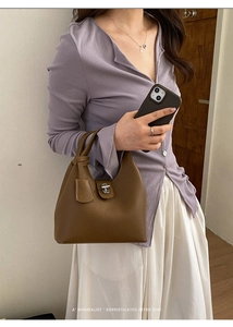 Detail view of brown lychee grain leather bucket bag with silver lock and handle