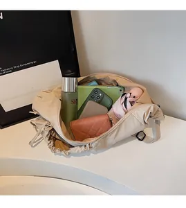 Spacious interior of beige dumpling bag showing storage for tablet and cosmetics