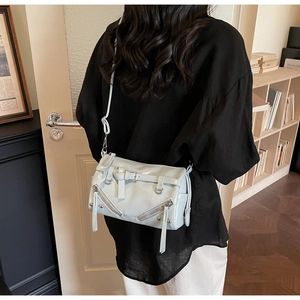 Detail of light blue glossy leather bag with fringes and metallic buckle accents