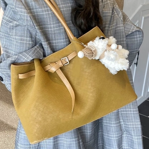 Large mustard yellow woven tote bag with buckle and plush charm for women