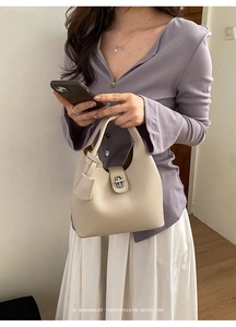 Close-up of beige pebble leather bucket bag featuring a silver twist lock and minimalist design