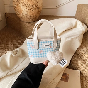 Mini blue gingham bucket bag with pink bow and white heart plush keychain charm