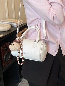 Chic cream leather boston bag with crossbody strap and cute puppy charm accessory