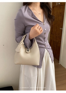 Detailed view of the creamy white litchi grain leather texture and silver turn-lock closure