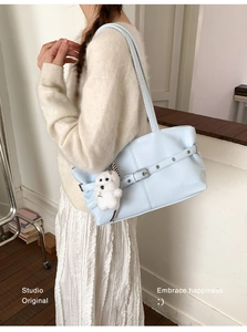 Detail of light blue lychee pattern tote bag with decorative buckle belt and plush puppy charm