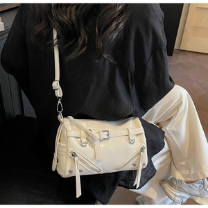 Detail view of a cream white bowling bag with silver studs and buckles on a model