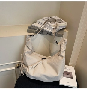 Detail of minimalist beige croissant bag showing textured fabric and adjustable strap