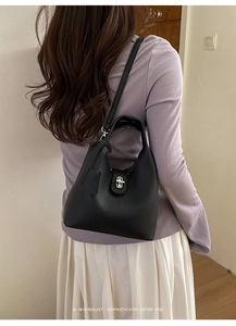Detail showing a black lychee texture leather bucket bag with silver turn-lock and strap