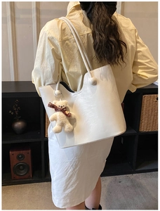 Close-up of a white tote bag with pleated texture and a cute plush bear charm decoration