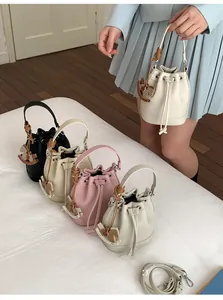 Close-up of drawstring bucket bags in pebble leather with woven handles and horse charms