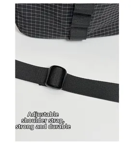 Détail de la bandoulière noire réglable sur un sac à bandoulière au motif à carreaux