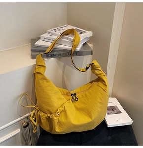 Detailed view of bright yellow crescent bag with ring zippers and adjustable wide strap