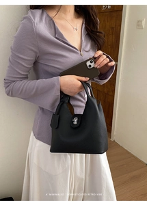 Detail of black lychee grain leather bucket bag with silver metal swivel lock closure