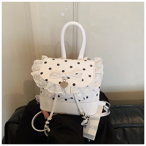 Détail d'un mini sac à dos blanc avec dentelle, pois noirs et décoration de nœud élégante