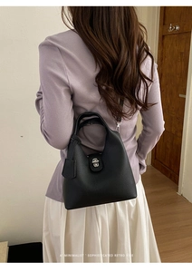 Detail of black lychee grain leather bucket bag with silver twist lock and strap
