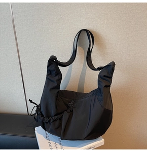 Detail of black nylon crescent bag featuring side drawstring ruching and adjustable wide strap