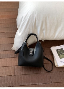 Detailed macro view of black lychee grain leather handbag with silver metal twist lock clasp