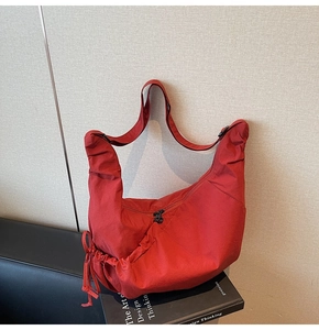 Detail view of large red dumpling bag showing nylon texture and double zipper closures