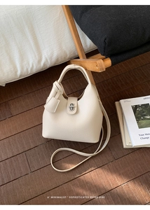 Detail of minimalist beige bucket bag with metal lock and textured pebble leather
