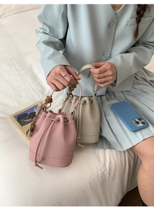 Detail shot of mini drawstring bucket bag with litchi texture and woven charm