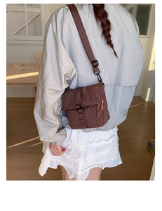 Détail d'un sac bandoulière à carreaux marron avec sangle réglable et boucle de fermeture