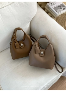 Close-up of minimalist leather bucket bags in brown and taupe with metallic turn-lock closure