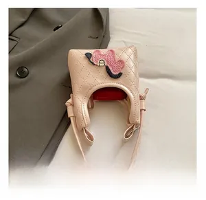 Detail view of pink quilted crossbody bag showing internal capacity and heart embroidery