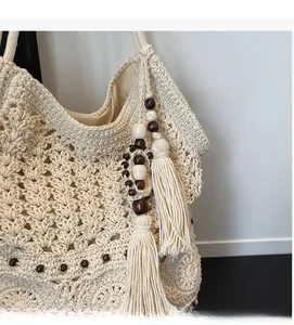 Detailed macro view of beige crochet bag with wood bead accents and long tassel charms