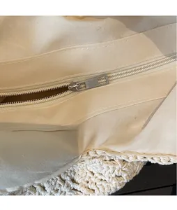 Detail view of the secure metal zipper closure and inner fabric lining of the woven tote bag