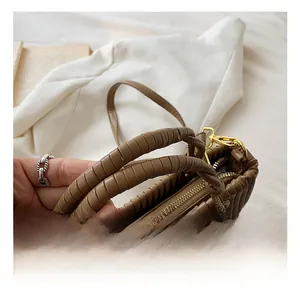 Detail of brown pleated PU leather handbag featuring thick twisted handle and gold hardware
